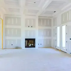 Interno di una stanza in costruzione con pareti in cartongesso insonorizzate, camino e porte a doppio battente.