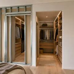 Struttura metallica per cabina armadio in cartongesso, con interni in legno e illuminazione a LED.