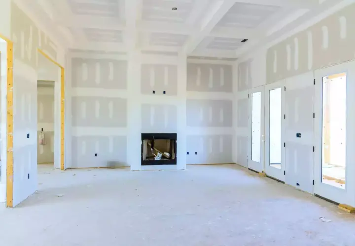 Interno di una stanza in costruzione con pareti in cartongesso insonorizzate, camino e porte a doppio battente.