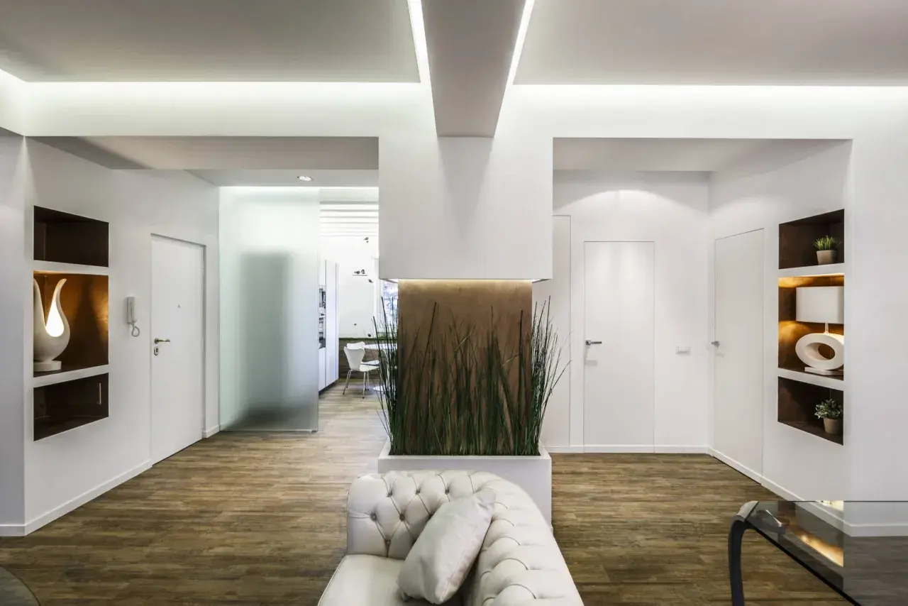 Interni moderni con pilastri in cartongesso che creano nicchie decorative e un'elegante parete divisoria con piante.
